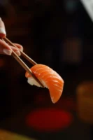 Salmon sushi held with chopsticks, - Credits: pexels