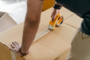 Man using packing tape to - Credits: pexels