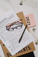 Close-up of tax forms, glasses, - Credits: pexels