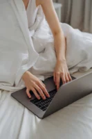 Adult woman comfortably typing on - Credits: pexels