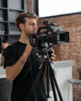 Male videographer filming indoors with - Credits: pexels