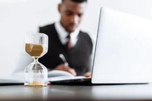 Businessman at desk with hourglass - Credits: pexels
