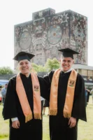 Two graduates smile in front - Credits: pexels
