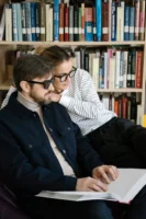 A couple reading a large - Credits: pexels