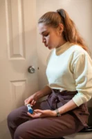 A woman sits indoors, looking - Credits: pexels