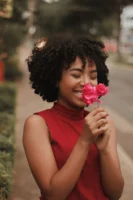 Smiling woman enjoying bougainvillea flowers - Credits: pexels